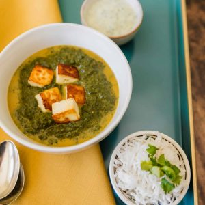 PALAK PANEER ON A BLUE TRAY WITH YELLOW NAPKIN